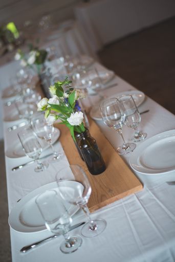 A vertical shot of a wedding table covered with a white tablecloth and utensil