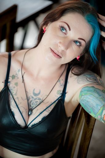 A young Caucasian female with blue hair and tattoos