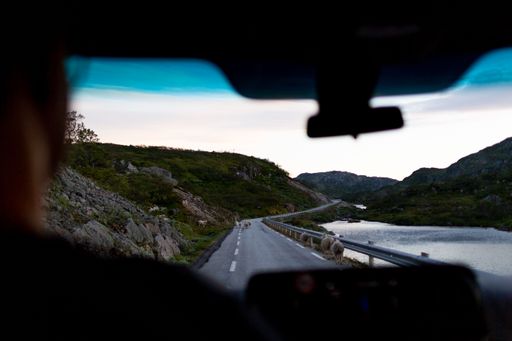 A scenic view of a winding road through the mountains captured from the inside of a vehicle.