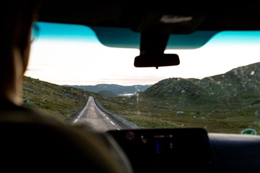 A view of the mountainous landscape from the passenger seat of a vehicle interior.