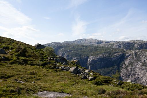 A scenic mountain valley in the countryside, featuring lush green grass, and rocky outcrops.