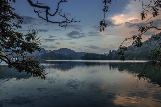 A stunning sunset is captured over a tranquil lake, with warm orange and yellow hues illuminating the still water