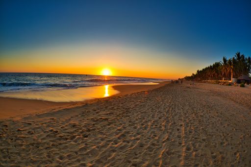 A landscape of a beach surrounded by the sea under the sunlight during a beautiful sunrise
