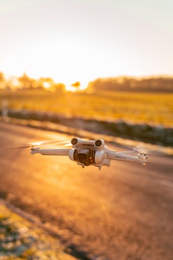An aerial view of a drone flying above a field at golden hour