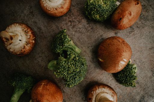 a top view of brown white mushrooms and green broccoli on a gray background