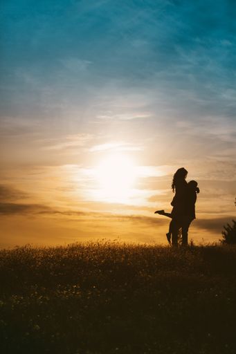A silhouette of a couple hugging each other on a sunset background