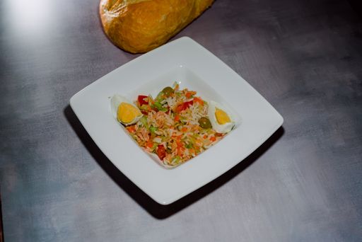 A high angle shot of a plate of fried rice with chicken, vegetables, and two pieces of boiled egg