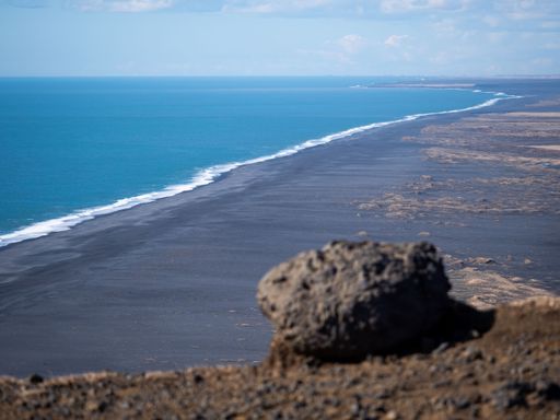 A pristine beachscape featuring the azure ocean waters and the rocky and sandy shoreline
