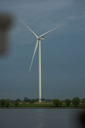 A vertical of a modern windmill at a lake on a cloudy day