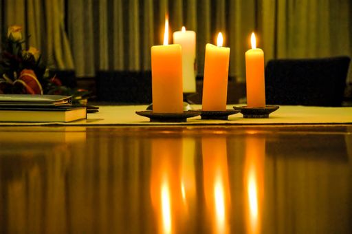 A closeup of candles on a wooden desk, illuminating a dark room