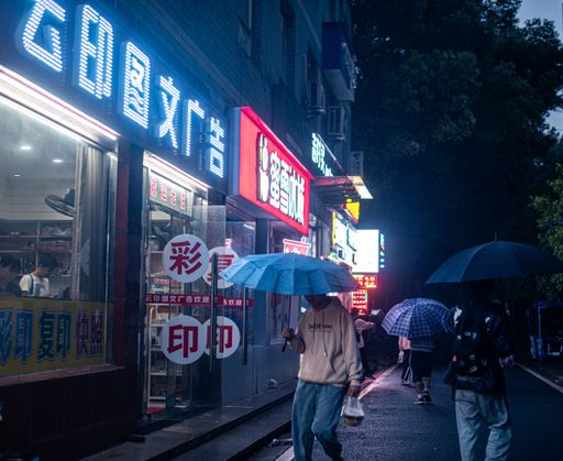 A scenic view of people walking with umbrellas on bustling streets of Wuhan, China at night