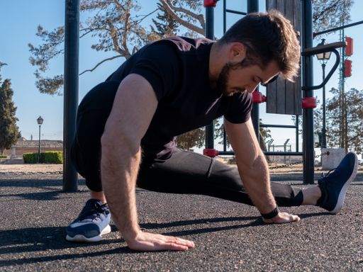 A young Caucasian man from Spain warming up exercises before starting calisthenics training in sunny park