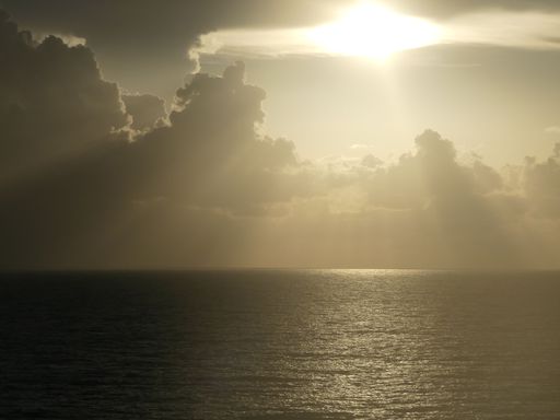 A tranquil scene of a sunrise over the ocean with dramatic cloudy background