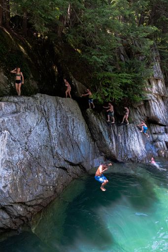 A group of friends climbing a diving cliff of a beautiful lagoon