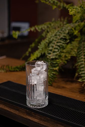 A vertical shot of an empty glass with ice at the bar