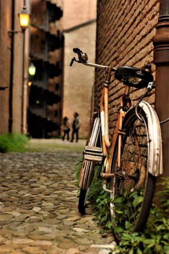 A vintage-style bicycle parked against a brick wall in a narrow alleyway.