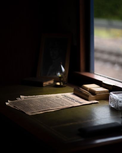 A wooden desk with newspapers scattered on top of it in a tidy and organized manner