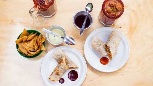 the top view of tasty burritos with clamato on the white plates and bloody mary in transparent glasses