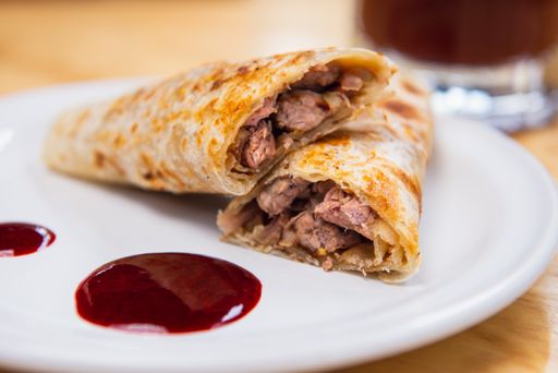 a closeup shot of burrito with clamato on a white plate