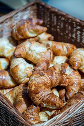 A closeup shot of a wicker basket of freshly-baked croissants.