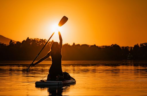 A beautiful silhouette of a woman in a canoe against the backdrop of a stunning sunset