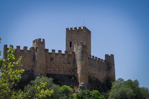 A beautiful shot of the majestic Alm Castle under a bright blue sky in Portugal