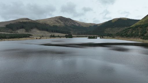 An idyllic landscape featuring a meandering river flowing through a lush valley flanked by rolling hills and majestic mountains in the distance