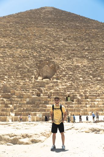 A young tourist male posing in front of the historic Pyramids in the Giza Plateau in Egypt
