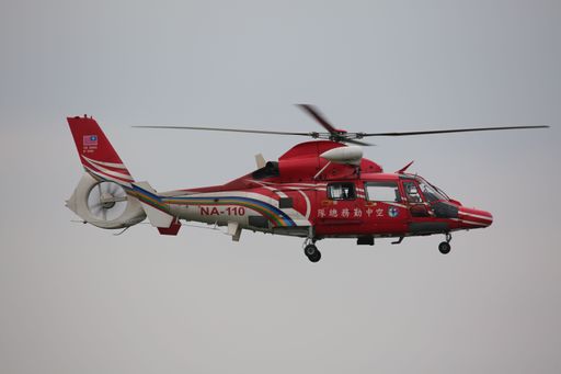 A helicopter soaring through a cloudy, grey sky.