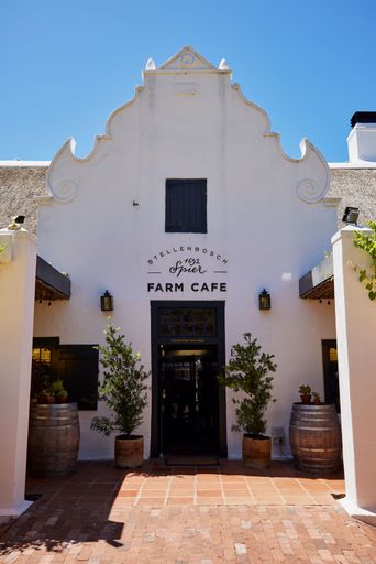 A white building with an inviting entranceway featuring a front door. Farm cafe in Stellenbosch