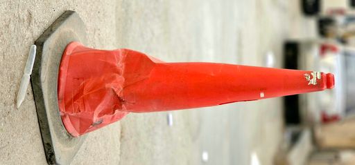 A vertical shot of an old dirty damaged traffic cone on the road