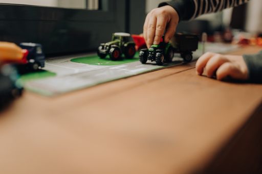 A selective focus shot of a child playing with toy cars on the windowsil