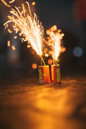 A vertical closeup shot of two small tnt cannons exploding with orange sparks