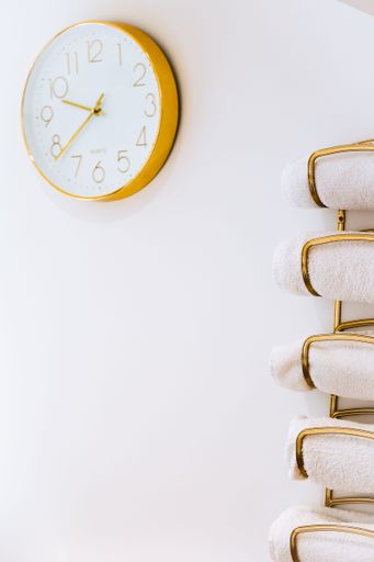 A clock on the wall with neatly folded white towels for spa treatment nearby