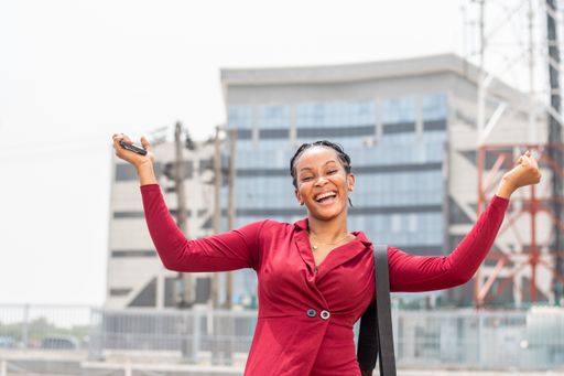 A portrait of a beautiful African lady with a phone feeling very happy.