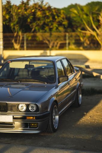 A vertical selective focus of a black car parked side of a street against a blurred background