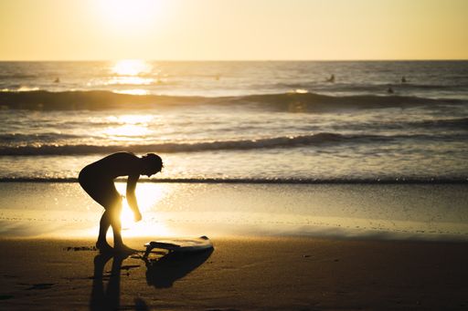 A woman surfer on the beach during a beautiful sunset