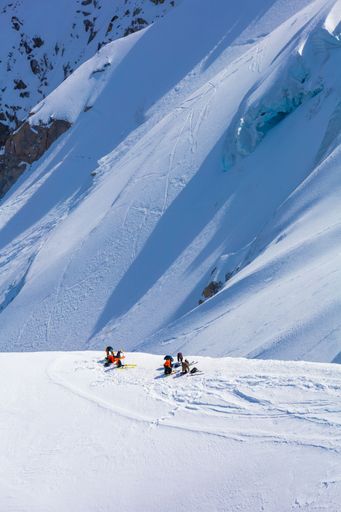 A vertical shot of a group of skiers getting ready to ride down a snow covered hill