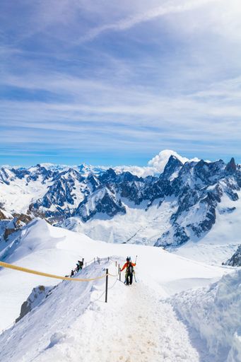 A group of skiers are skiing down a mountain slope, surrounded by snow-covered terrain