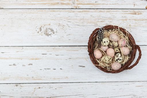 A top view of a basket with Easter eggs on a wooden surface