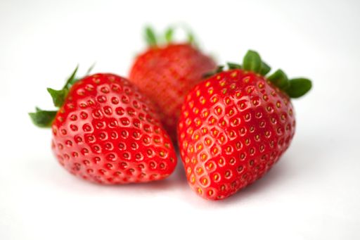 A close-up of three ripe strawberries on a white background