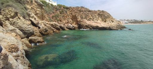 A beautiful sunny day at a rocky shoreline with calm waves lapping against the shore