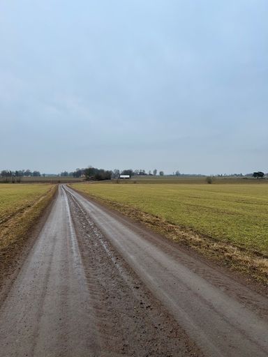 A rural dirt road with a rustic barn in the background