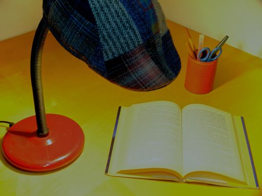 An opened book under a lampshade with pencil holder on the side
