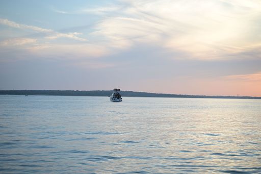 A small sailboat sailing in the tranquil lake or sea at sunset