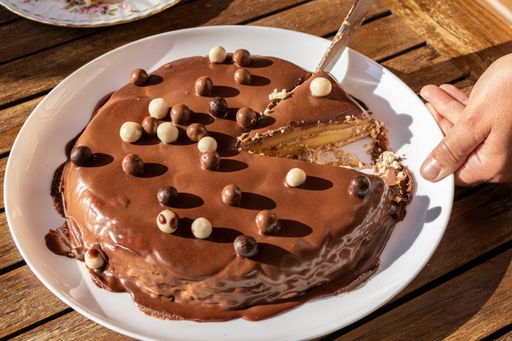 Closeup of human hand cutting a portion of Homemade chocolate tart topped whit chocolate balls on outdoor