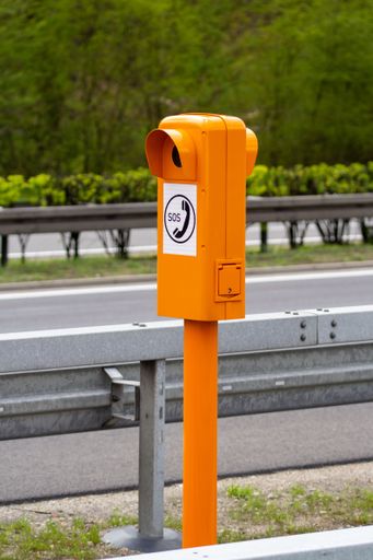 An outdoor yellow sos post stands in a city street
