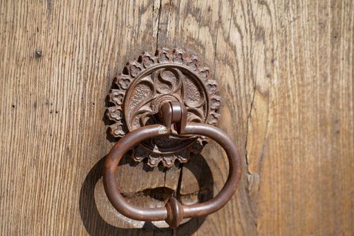 A closeup shot of a rusty door knocker on an old wooden door