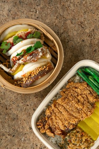 An overhead shot of fried chicken and appetizing bao burgers in a wooden bowl