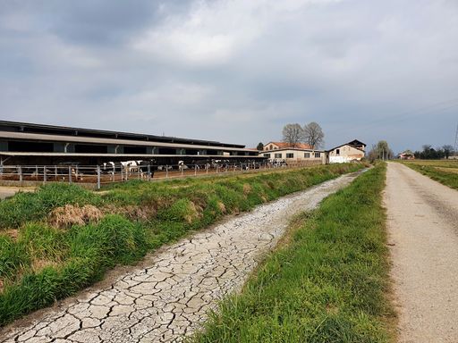 A cracked road in a rural area against the cloudy sky